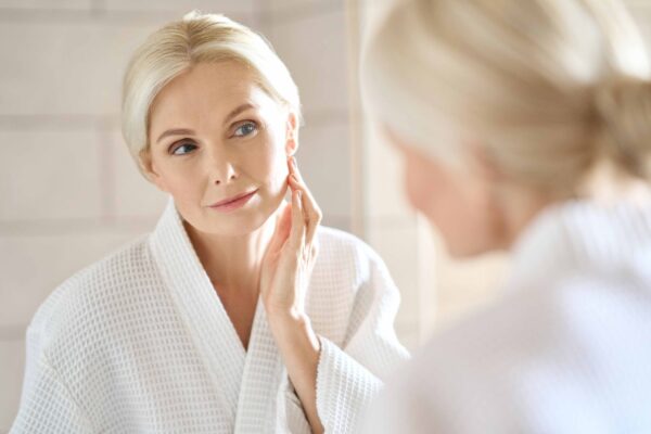 woman using cream with probiotics for anti aging in front of the mirror